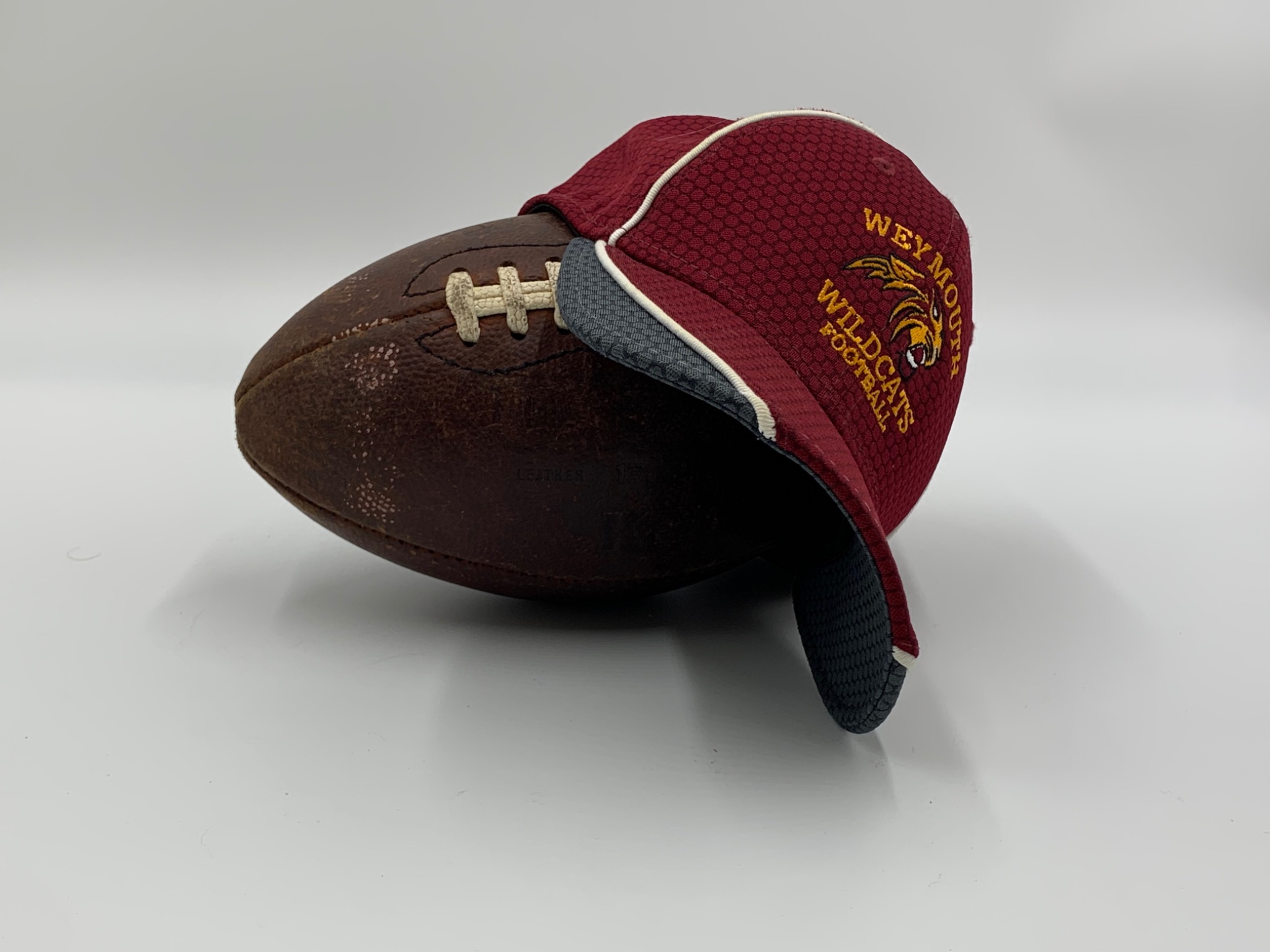 Weymouth Wildcats coaching cap resting on a football